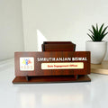 The Premium Wooden Desk Name Plate with Pen Holder displays "SMRUTIRANJAN BISWAL, State Engagement Officer" and the NSDC logo, accented by a plant—an ideal Custom Office Table Name Plate and thoughtful Corporate Gift.