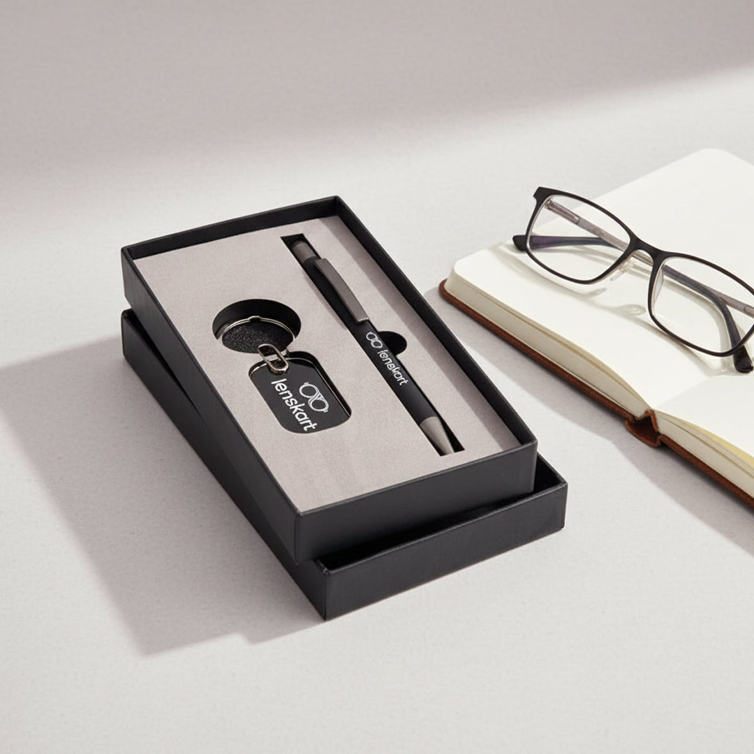 The Pen & Key Chain - Combo Gift Set - AIGS - 2501, presented in a black gift box, rests on a desk near an open notebook and eyeglasses—an elegant corporate gifting option with neatly arranged items under soft lighting.