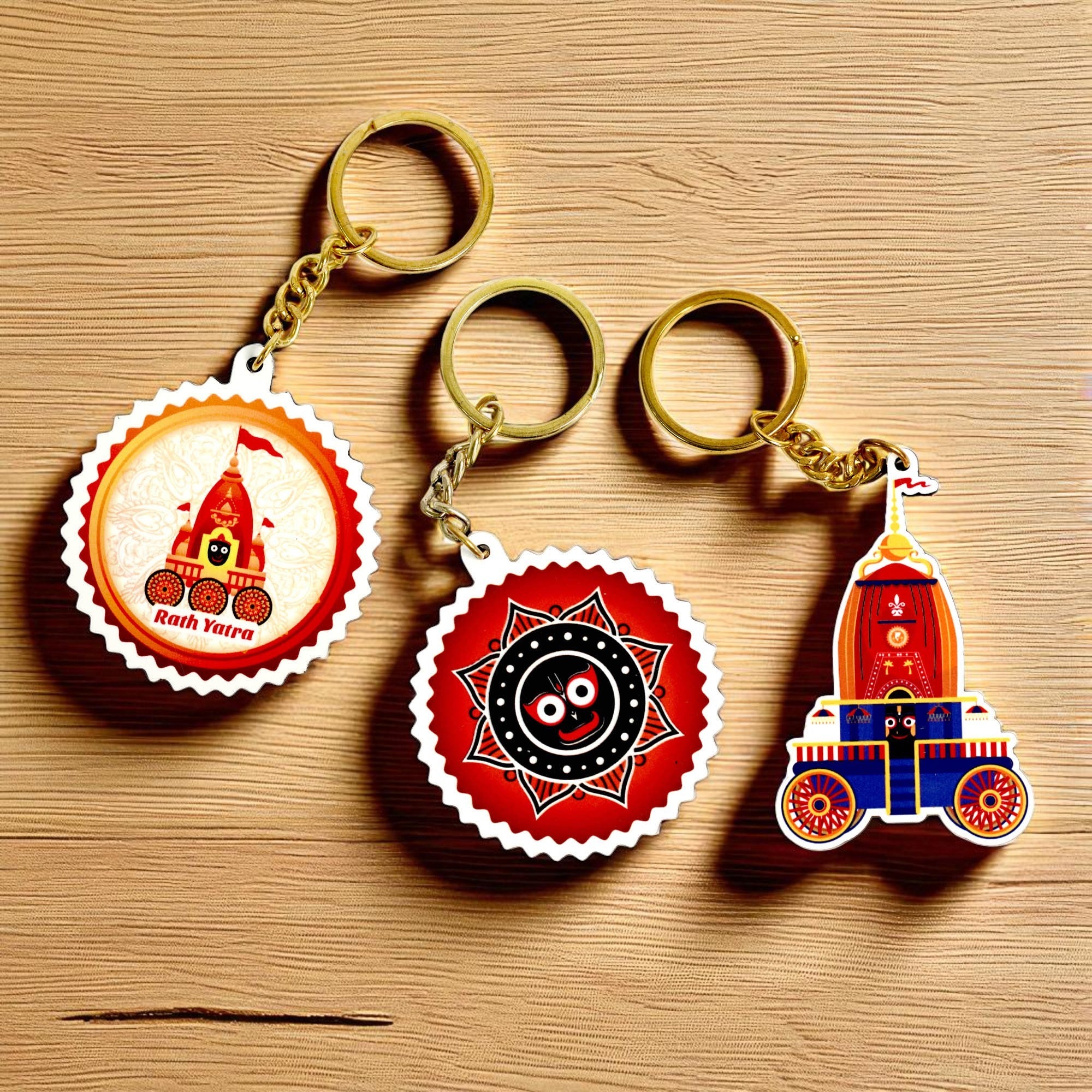 The Jai Jagannath Key Chains | Set of 3 are displayed on a wooden surface, featuring chariots, Jagannath symbols, and vibrant festive colors—a perfect Odisha cultural gift inspired by the Rath Yatra festival.