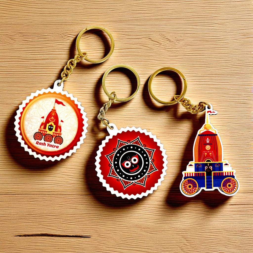 The Jai Jagannath Key Chains | Set of 3 are displayed on a wooden surface, featuring chariots, Jagannath symbols, and vibrant festive colors—a perfect Odisha cultural gift inspired by the Rath Yatra festival.