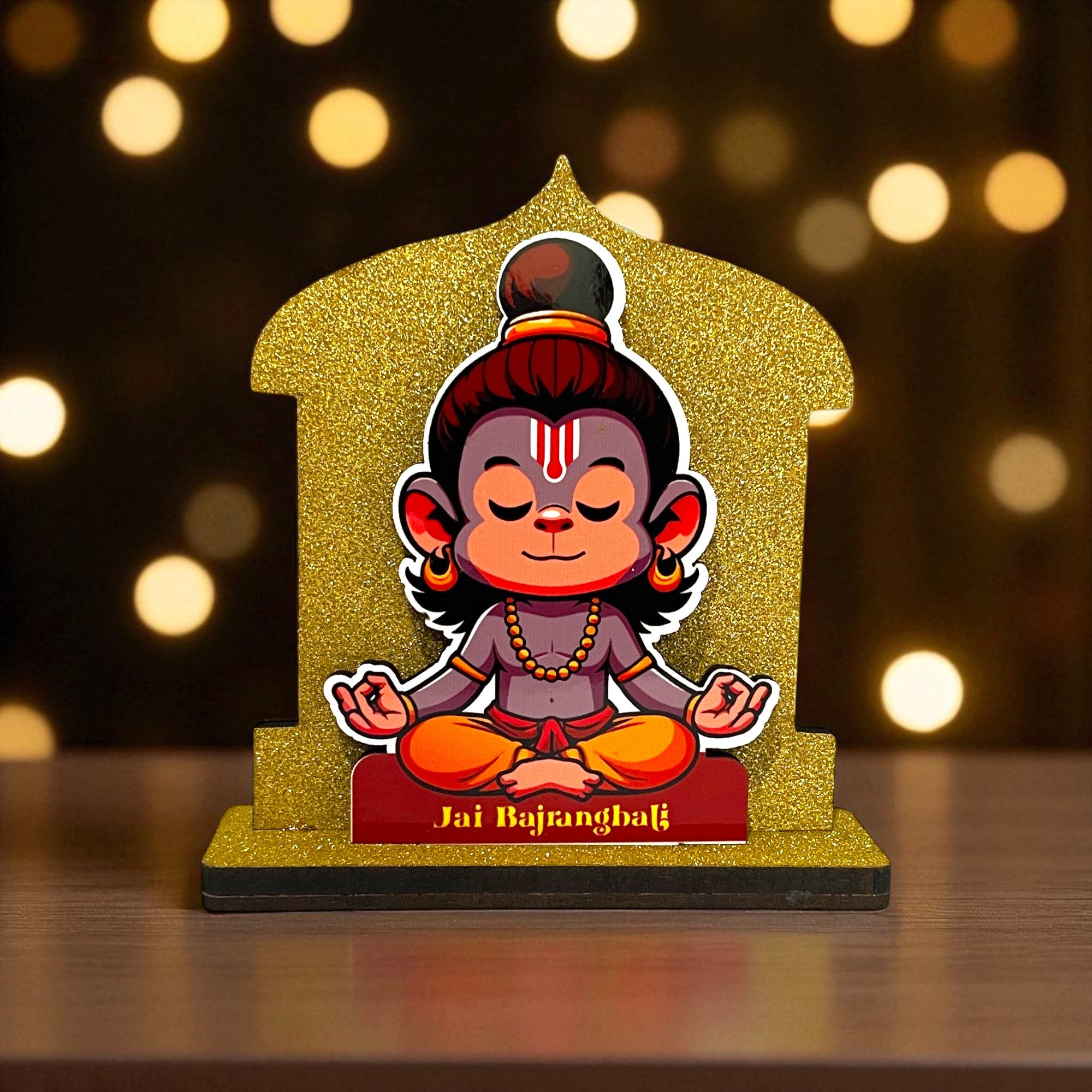 The Hindu Gods Mini Temple features a cartoon Lord Hanuman meditating on a sparkly gold stand, with "Jai Bajrangbali" below and a soft, golden-hued background for a divine touch.